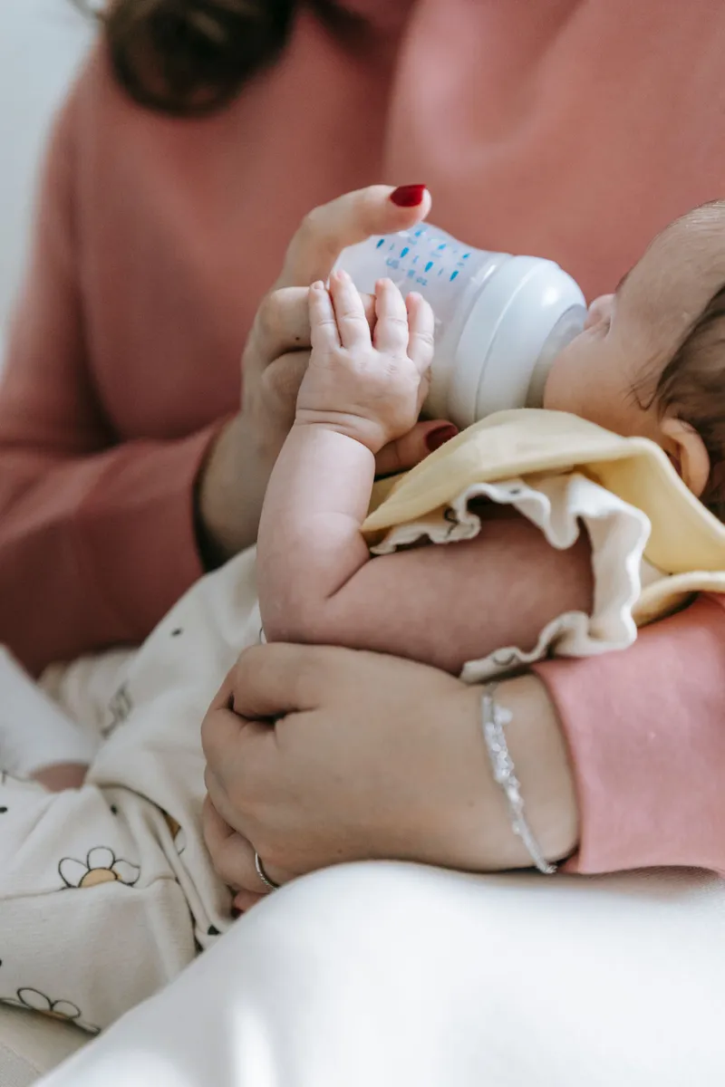 Parent bottle-feeding a newborn baby